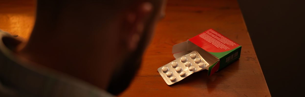 Мужчина смотрит на упаковку таблеток Антипохмелин